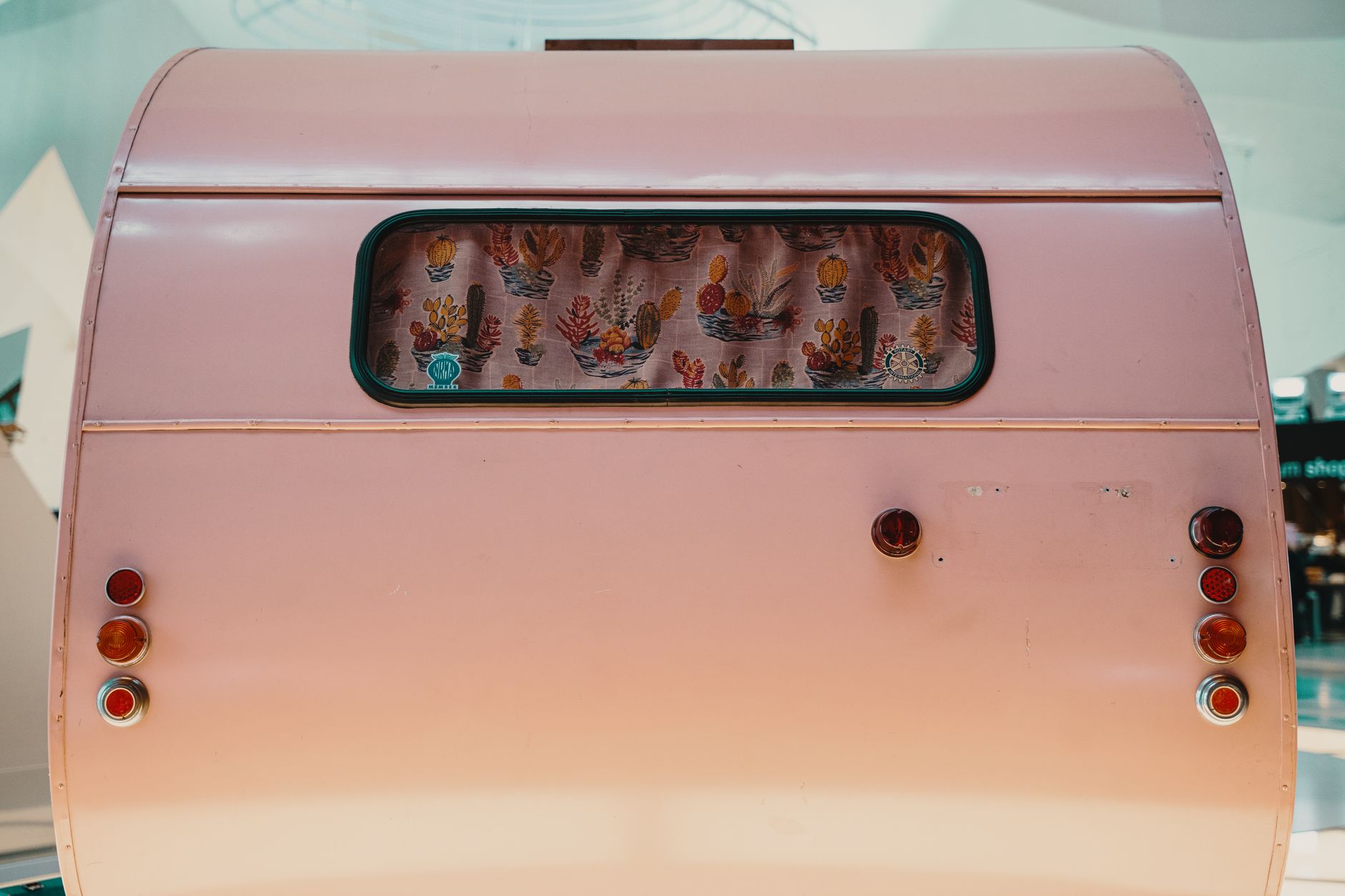 Pink vintage teardrop trailer with cactus-print curtain